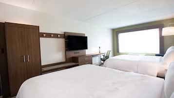 A hotel room with two beds, a TV, a desk, and a window.
