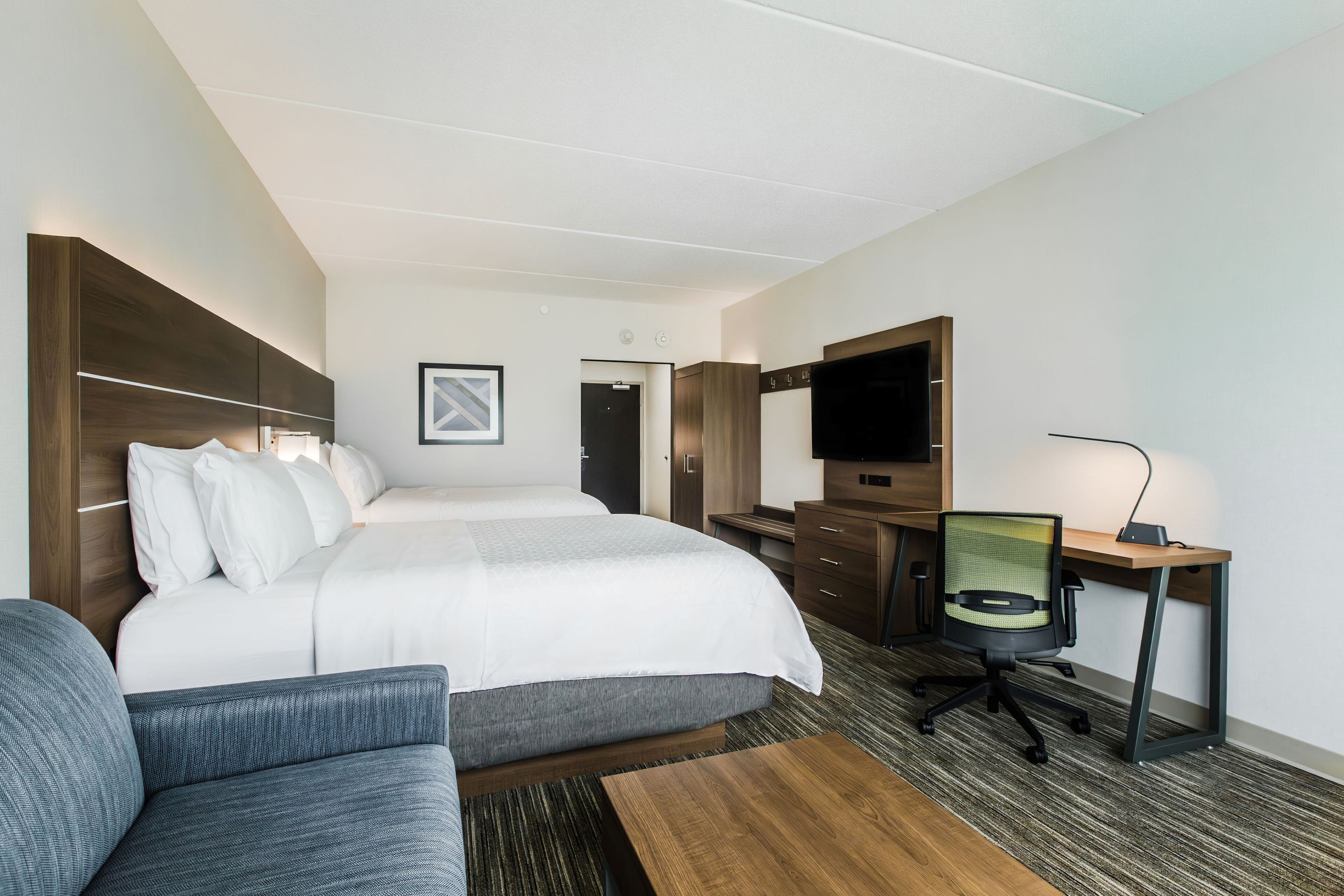 Habitación de hotel con una cama grande, un escritorio con una silla, una televisión y un sofá.