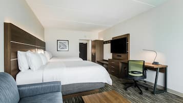 Habitación de hotel con una cama grande, un escritorio con una silla, una televisión y un sofá.