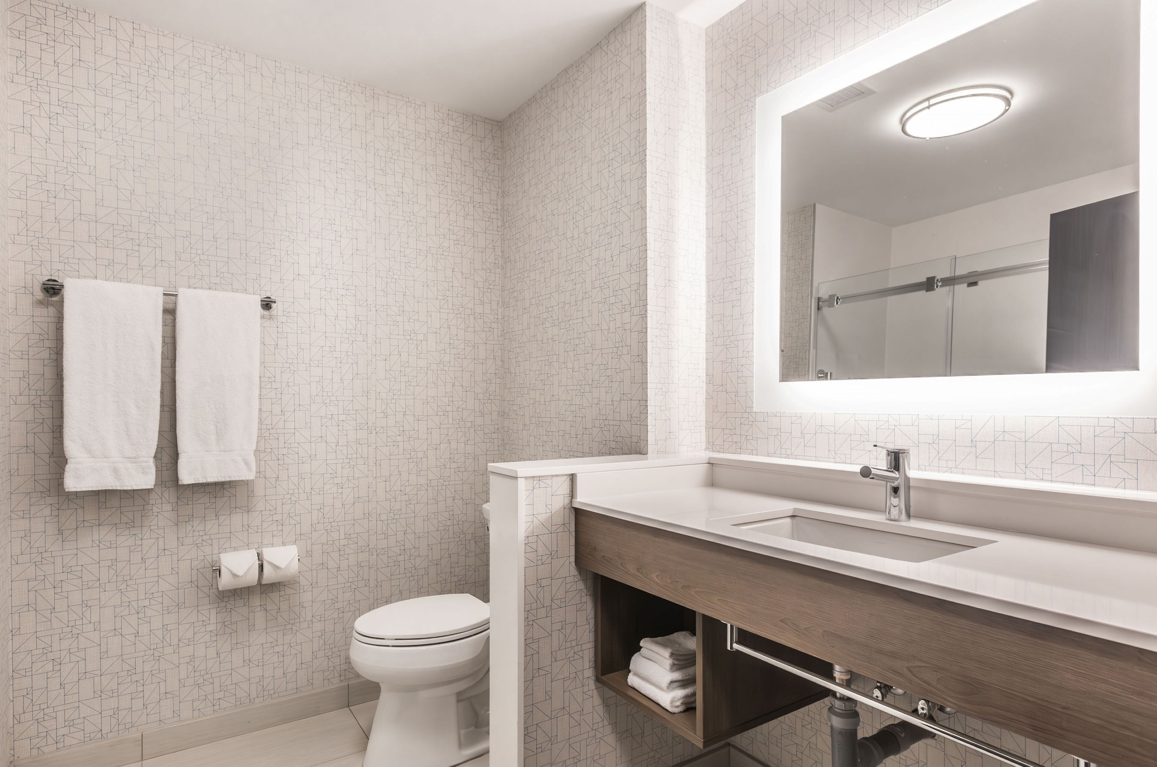A modern bathroom with a toilet, a sink with a mirror, and a towel rack.