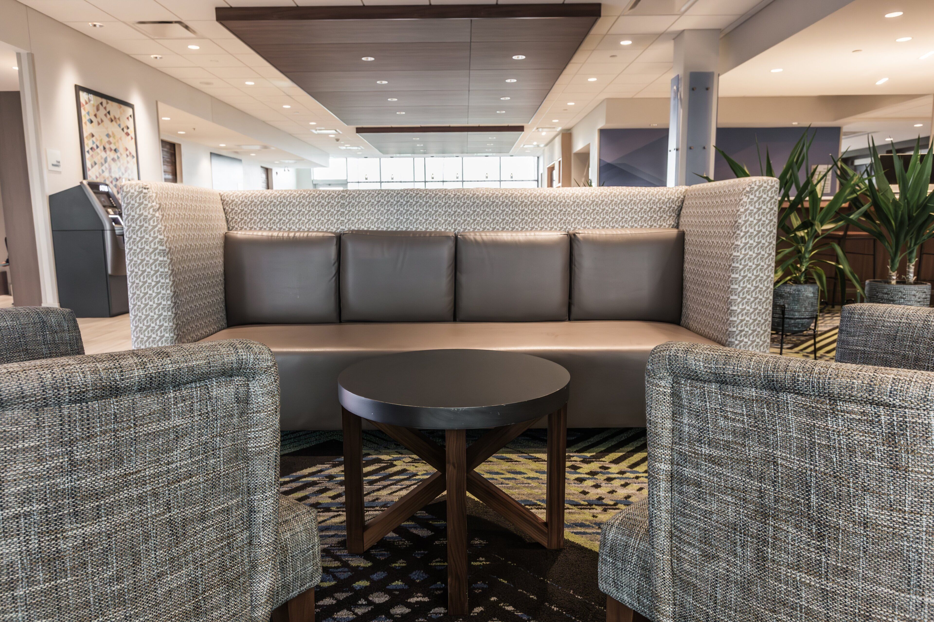 A modern lounge area with a sofa, two armchairs, and a small round table.