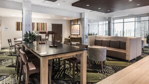 A modern hotel lobby with a dining area, a sofa, and a reception desk. - Holiday Inn Express & Suites Welland by IHG (Welland)