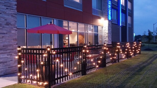 A hotel with a modern design, featuring a brick facade, large windows, and a red umbrella over a seating area. - Holiday Inn Express & Suites Welland by IHG (Welland)