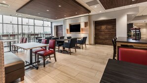 A modern dining area with wooden flooring, red and black chairs, and a large TV on the wall. - Holiday Inn Express & Suites Welland by IHG (Welland)