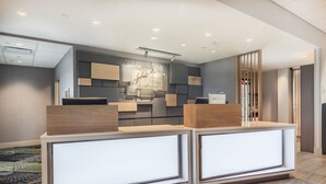 A reception area with a modern design, featuring a reception desk, a wall-mounted display, and a counter with a beverage dispenser. - Holiday Inn Express & Suites Welland by IHG (Welland)
