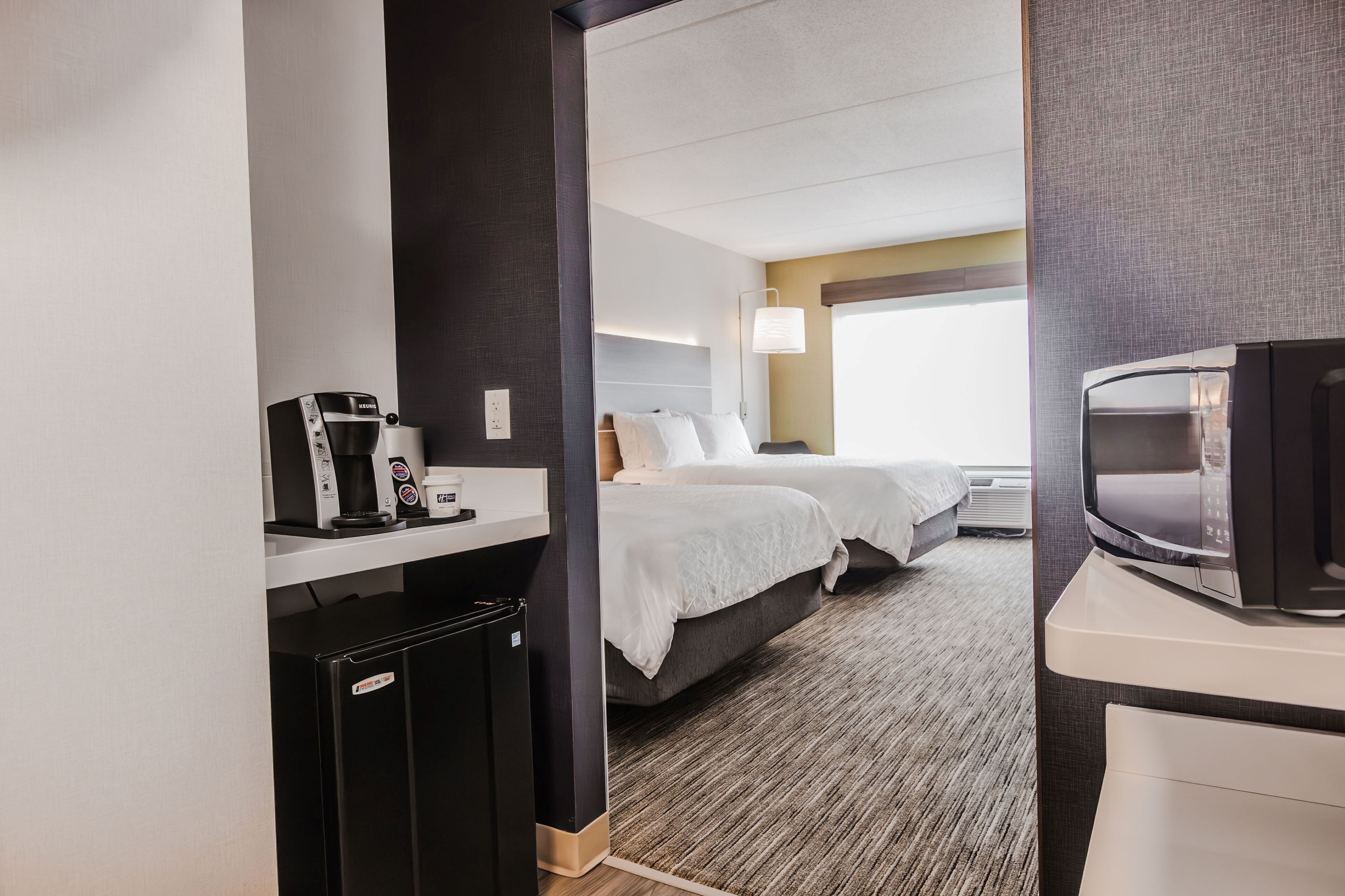 Una habitación de hotel con kitchenette, una cama, un televisor y un ventanal.