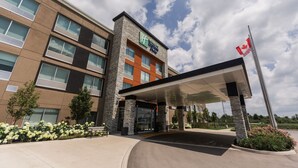 A modern hotel with a stone facade, a covered entrance, and a Canadian flag. - Holiday Inn Express & Suites Welland by IHG (Welland)