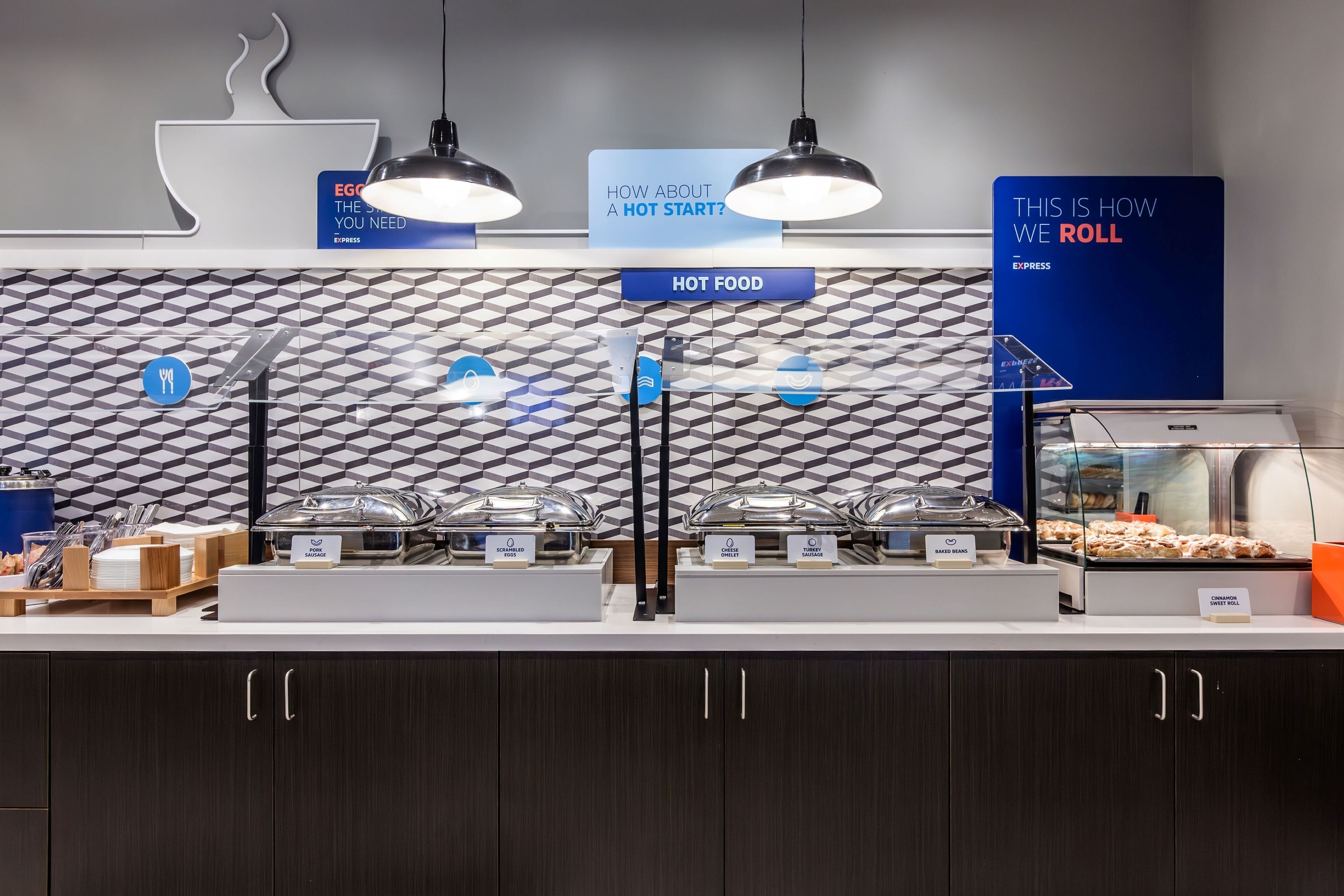 A buffet area with labeled hot food stations, a coffee station, and a sign indicating the start of the buffet.
