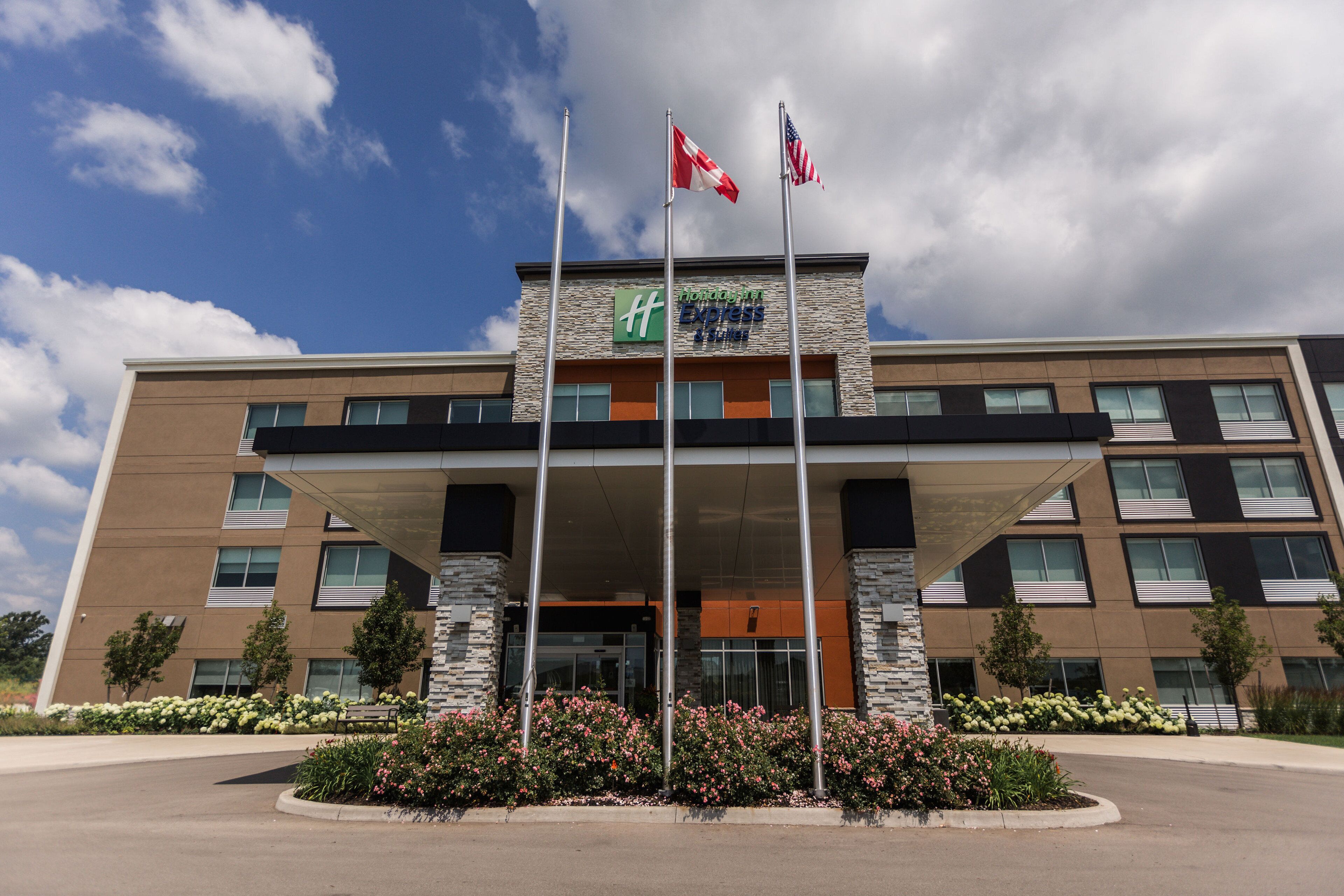 A modern hotel with a stone facade, multiple floors, and a prominent entrance with flags.