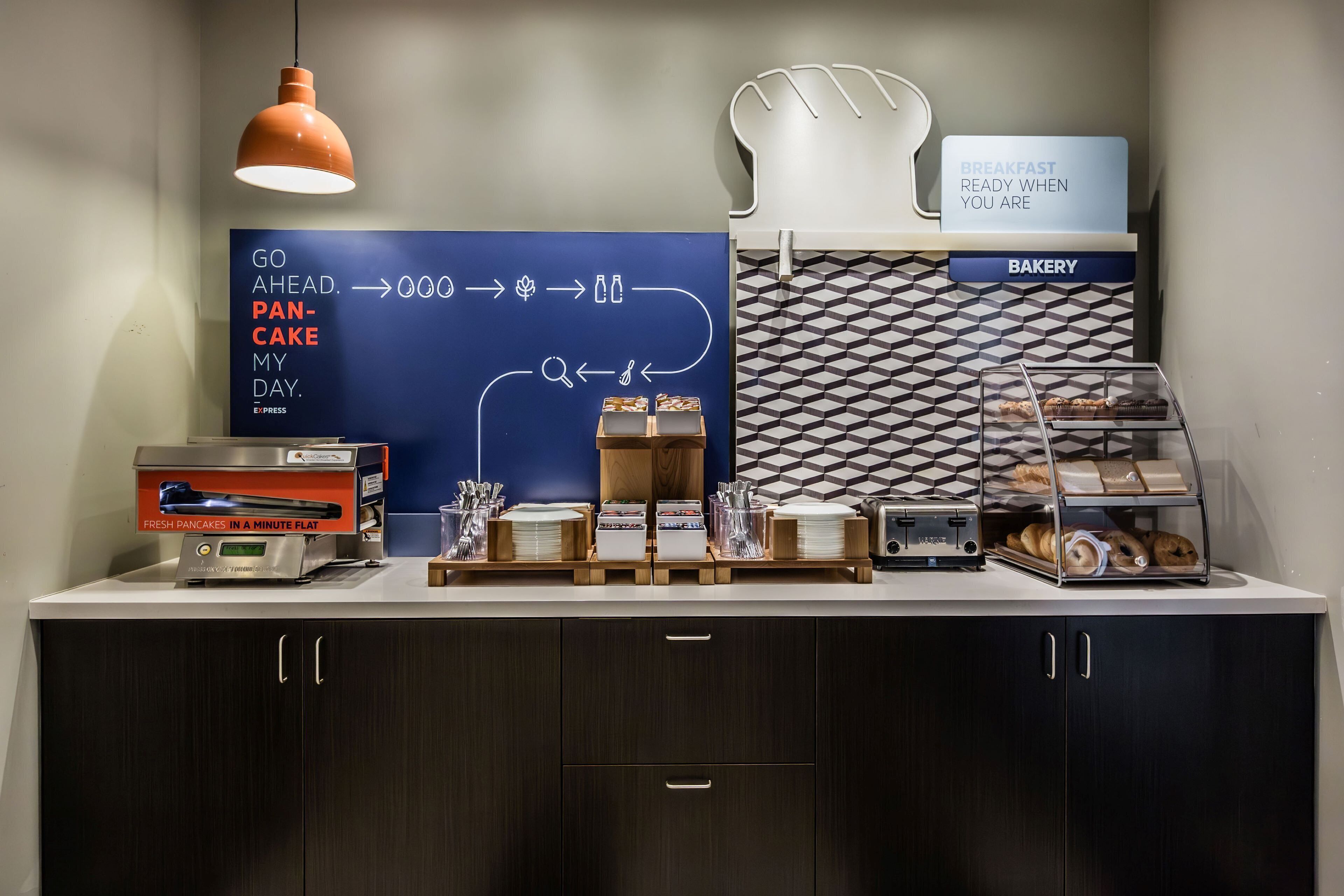 A breakfast station with a digital display, a sign for breakfast readiness, and a bakery section.