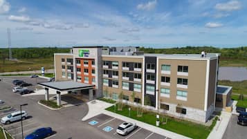 Un hôtel moderne doté d’une cour intérieure, de nombreux espaces de stationnement et offrant une vue sur le paysage environnant.
