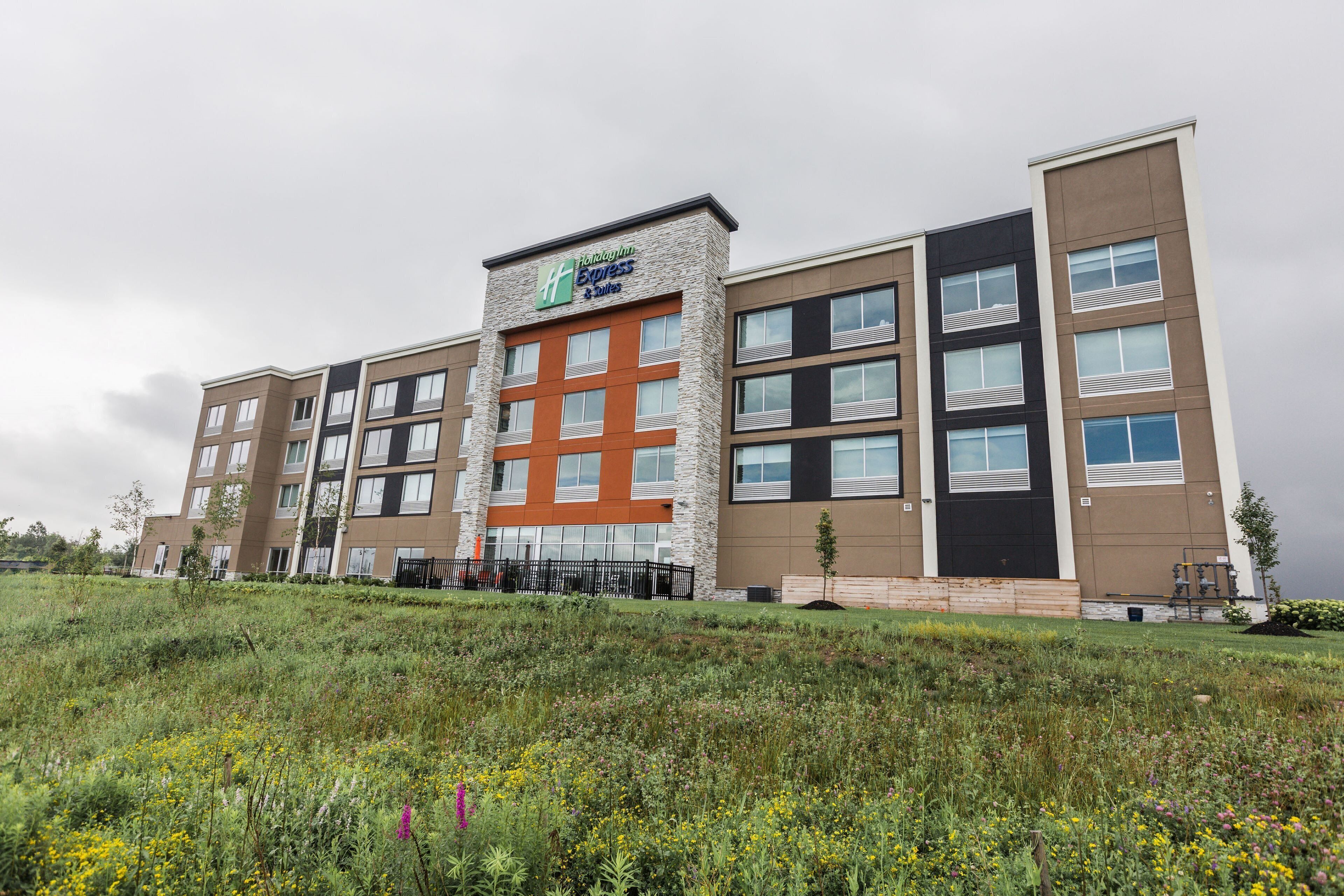 A multi-story hotel with a prominent 'Hilton Express' sign, featuring a modern design with a mix of stone and brick facades, large windows, and a flat roof.