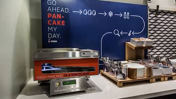 A breakfast station with a QuickCake Express machine, utensils, and a sign promoting the service.
