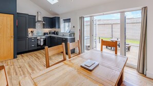 A modern kitchen with dark cabinets, a wooden dining table, and a sliding glass door leading to a patio. - 3 bedroom accommodation in Trevor, near Llangollen (Trevor, near Llangollen)
