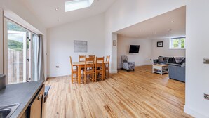 A spacious living area with a dining table, chairs, a sofa, and a TV mounted on the wall. - 3 bedroom accommodation in Trevor, near Llangollen (Trevor, near Llangollen)