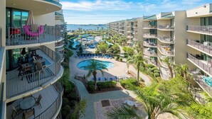 Un resort con varios balcones, una zona de piscina central y vista al océano.