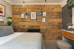 Un dormitorio con pared de madera, cama, radiador y cómoda.