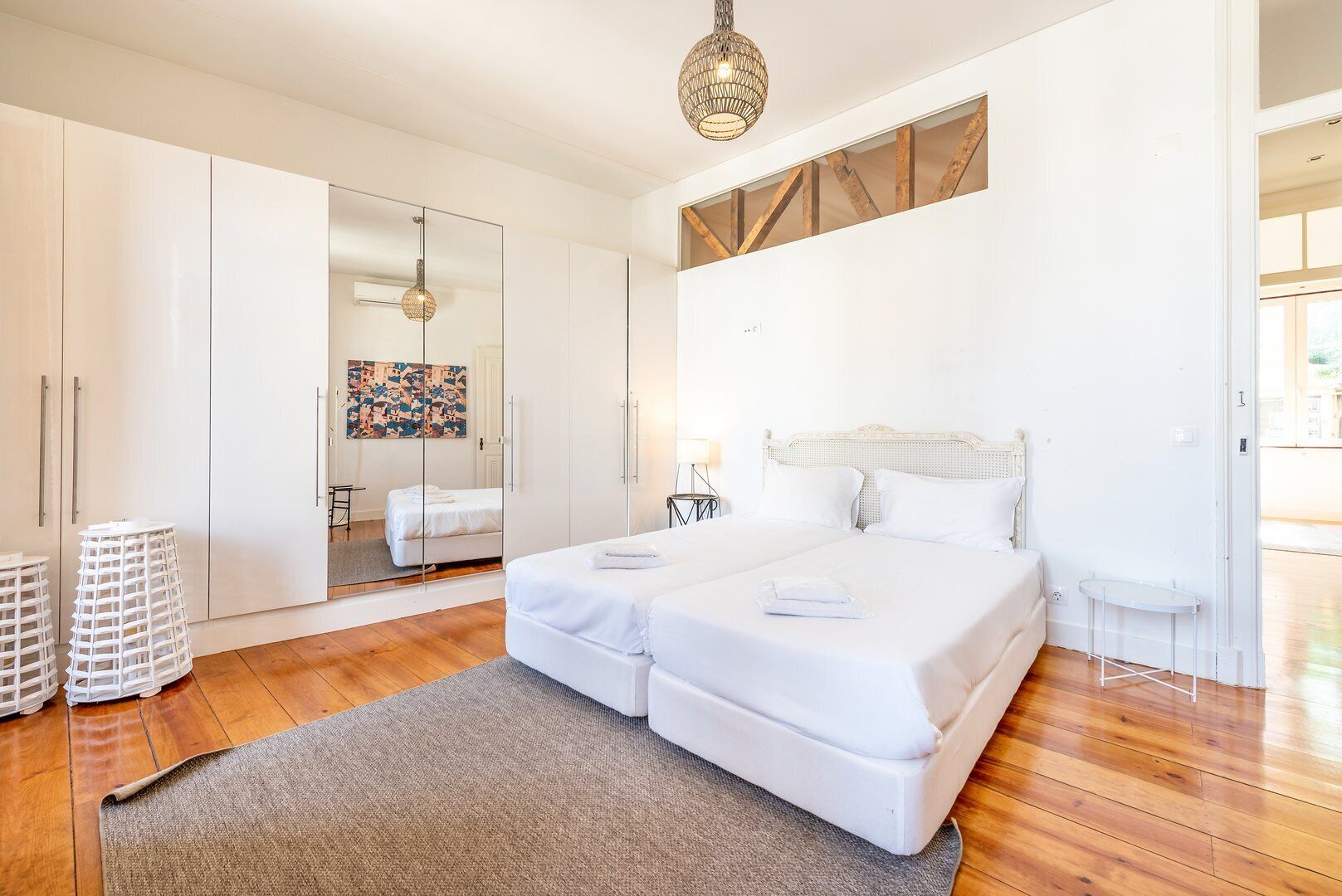 Un dormitorio moderno con una cama grande, un armario de vidrio y suelo de madera.