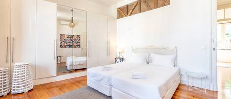 Un dormitorio moderno con una cama grande, un armario de vidrio y suelo de madera.