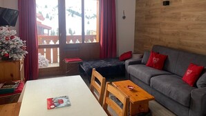 A cozy living room with a grey sofa, red cushions, a wooden table, and a small wooden bench. - BELLE PLAGNE 2 rooms, sleeps 5-6, ski-in/ski-out + covered parking included (LA PLAGNE)