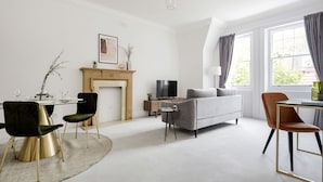 A modern living room with a fireplace, a sofa, a TV, and a dining area with chairs. - The Cadogan Suite next to Sloane Square (London)