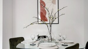 A dining table with a glass top, surrounded by green upholstered chairs, set with white plates and clear glasses. - The Cadogan Suite next to Sloane Square (London)