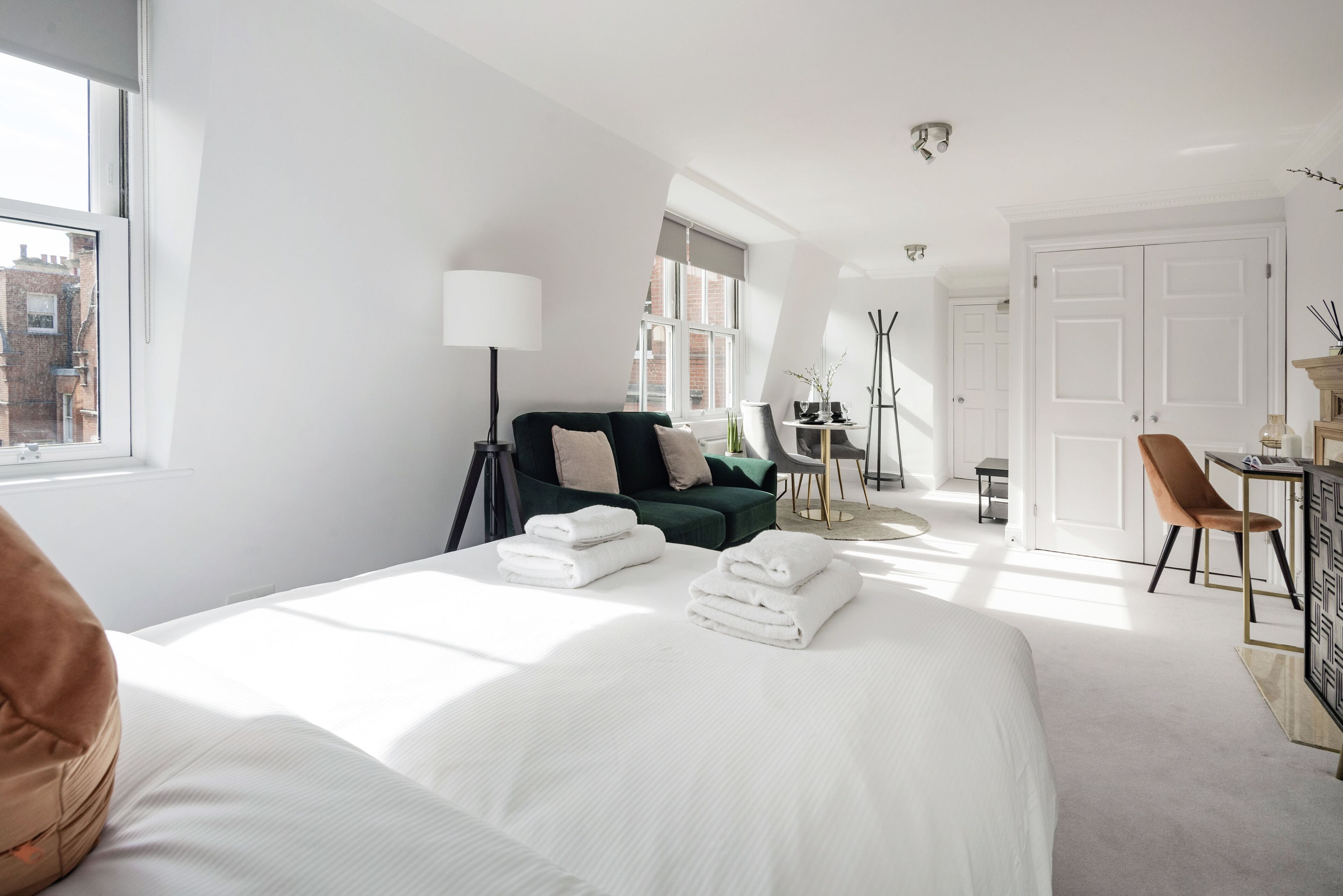 Een moderne hotelkamer met een groot bed, een bureau, een stoel en uitzicht op de stad door het raam.