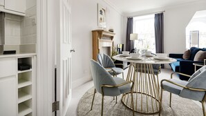 Una sala de estar moderna con una mesa de comedor redonda, sillas tapizadas en gris, un sofá azul y una chimenea.