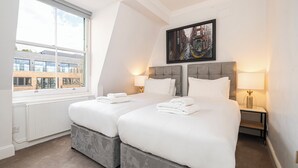 Habitación de hotel con dos camas, un ventanal grande, vistas a la ciudad y una obra de arte enmarcada en la pared.