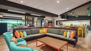 Un'area lounge moderna con un divano componibile, un tavolino in legno e un'area bar sullo sfondo.