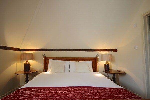 A hotel room with a large bed, two bedside tables with lamps, and a wooden headboard. - Picturesque cottage for two in the Kent countryside - Moat Farm Cottage (Ash)