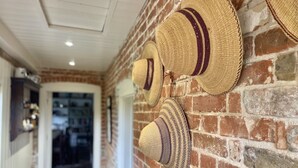 A brick wall with several straw hats hanging on it. - Picturesque cottage for two in the Kent countryside - Moat Farm Cottage (Ash)