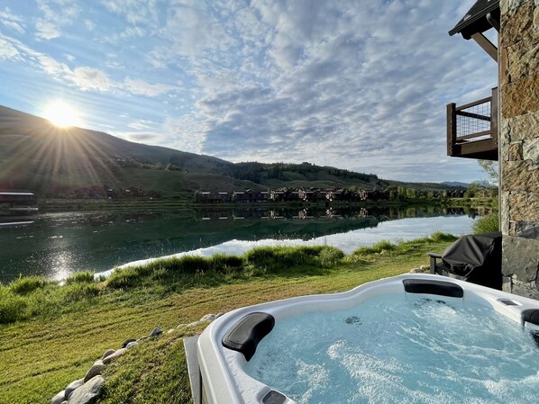 Un jacuzzi con vistas a un lago y casas al fondo.