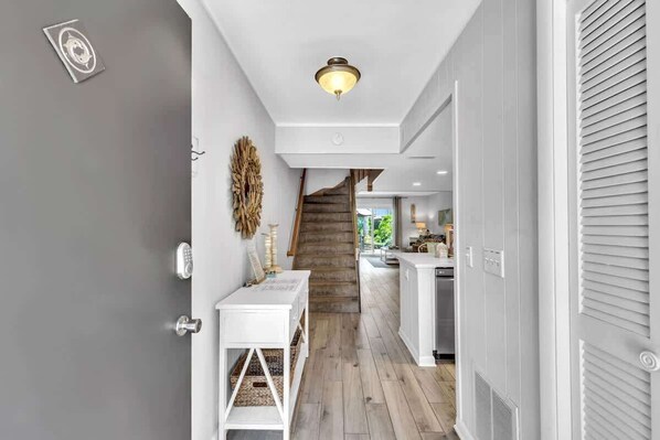 A hallway with a wooden staircase, a white console table, and a ceiling light fixture.