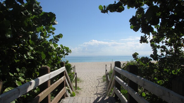 A wooden pathway leading to a beach with a clear view of the ocean. - Beautiful Studio on Collins Ave by the Beach with Private Parking (Miami Beach)