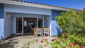 A modern house with a patio, a dining area with a table and chairs, and a garden with pink flowers. - Luxury Vacation Apartment "Casa Blou Curacao" Blije Rust 13 near Blue Bay Resort (Willemstad)