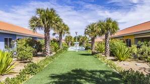 A pathway leading to a swimming pool surrounded by palm trees and well-maintained greenery. - Luxury Vacation Apartment "Casa Blou Curacao" Blije Rust 13 near Blue Bay Resort (Willemstad)