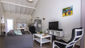 A modern living room with a grey sofa, a white coffee table, a black and white recliner, a flat-screen TV, and a colorful artwork on the wall. - Luxury Vacation Apartment "Casa Blou Curacao" Blije Rust 13 near Blue Bay Resort (Willemstad)