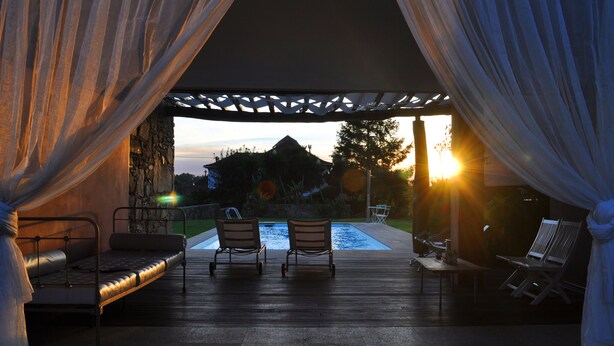 Un espace extérieur aménagé avec une piscine, un patio couvert et une vue sur la montagne au coucher du soleil.