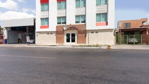 Un hotel con diseño moderno, que muestra un llamativo logotipo 'OYO' y un cartel que indica que es hotel y oficina pública.