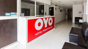 Zona de recepción de un hotel con un letrero rojo y blanco que dice "OYO HOTEL PUERTA DE SOL".