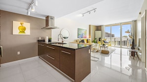 A modern kitchen with a central island, a dining area with a view, and a large window.