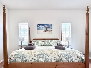 Restful haven with a four-poster bed, flanked by nightstands and a beach-themed painting.