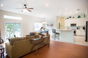 Relax in this inviting living area with a sofa set, coffee table, and dining area, featuring a well-equipped kitchen with a microwave and refrigerator.