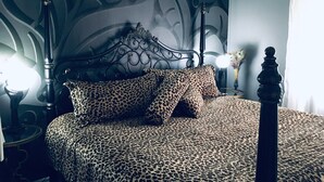 En seng med et leopardmønstret sengetæppe, en dekorativ sengegavl og en væg med blomstermønster.