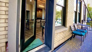 Un edificio moderno con fachada de ladrillo, amplias ventanas y una mesa de billar visible a través de una puerta abierta.