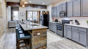 Una cocina moderna con una isla central, armarios grises y una pared decorativa de piedra.