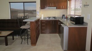 A kitchen with wooden cabinets, a gas stove, a microwave, and a refrigerator. - Casitas del Valle  (Valle de Guadalupe)