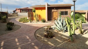A modern house with a paved driveway, a small garden with cacti, and a street lamp. - Casitas del Valle  (Valle de Guadalupe)