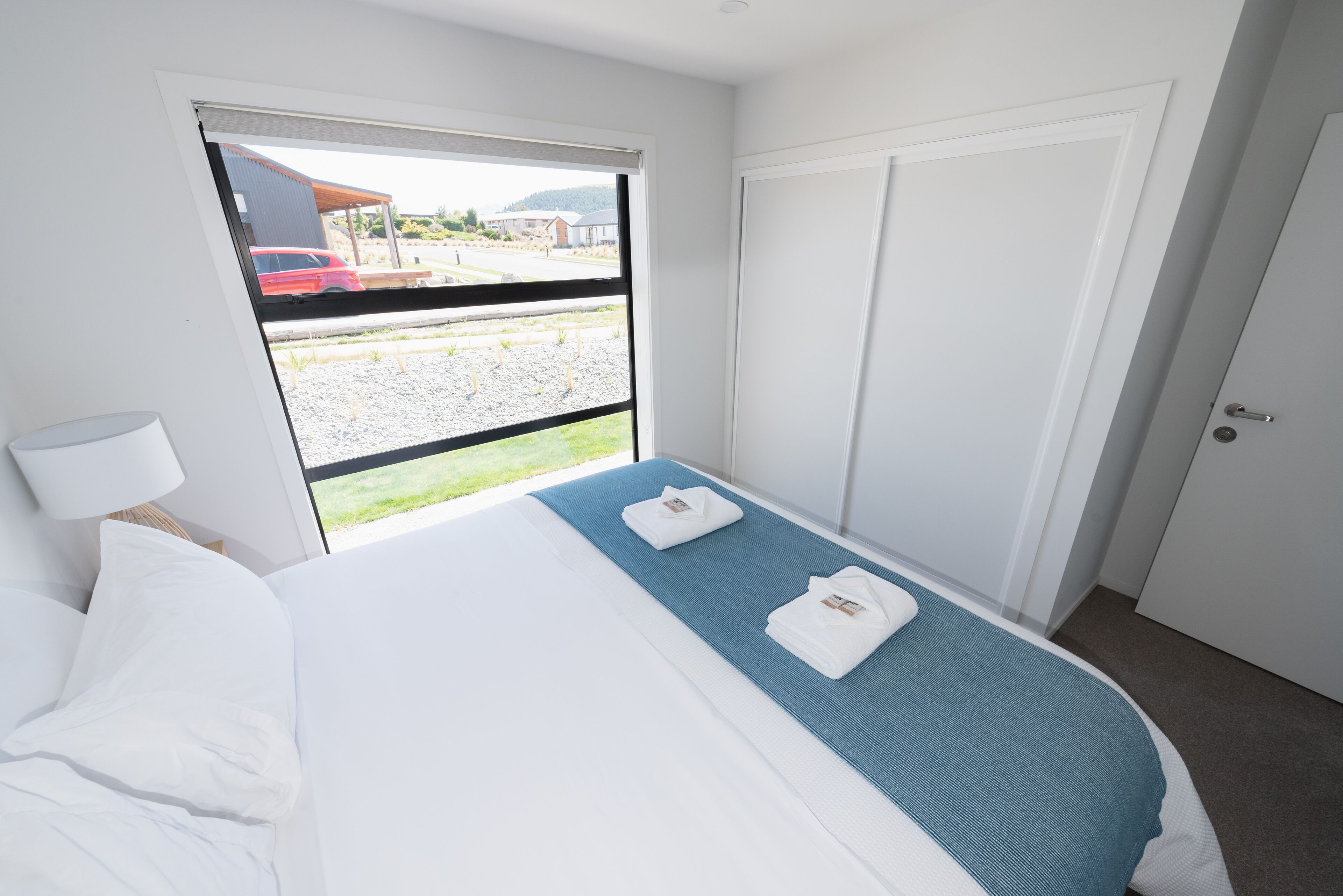 A hotel room with a bed, a window, and a door.